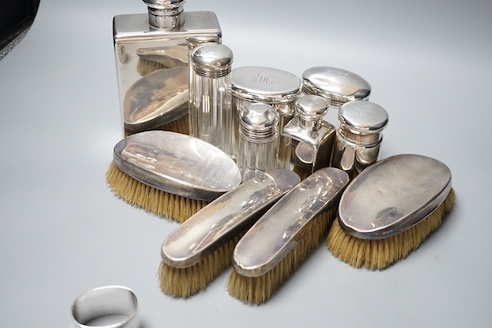 Six assorted George V silver mounted glass toilet jars, a similar brush set, a silver napkin ring and a large silver hip flask?, London, 1919, 17.3cm, 12.5oz.